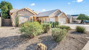 A residential property with a two-car garage, a covered patio, and a landscaped garden with cacti and shrubs. - Mesa Desert Oasis • Pool • Grill (Mesa)