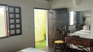 Une chambre à coucher comprenant un lit, un bureau, une chaise, un miroir et donnant sur un jardin.