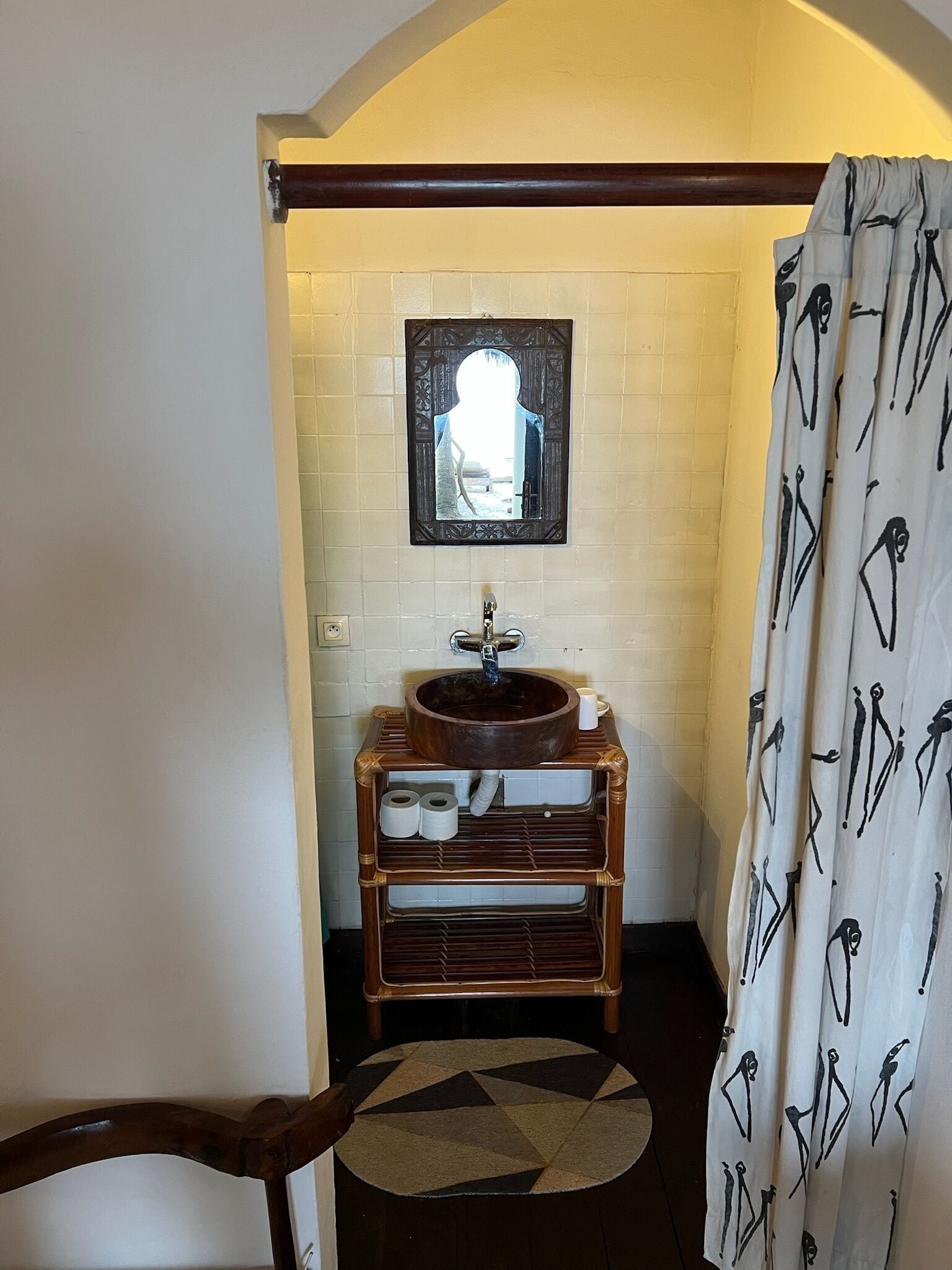A bathroom with a wooden sink, a mirror, and a shower curtain with a pattern.