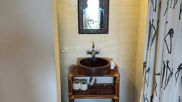 A bathroom with a wooden sink, a mirror, and a shower curtain with a pattern.