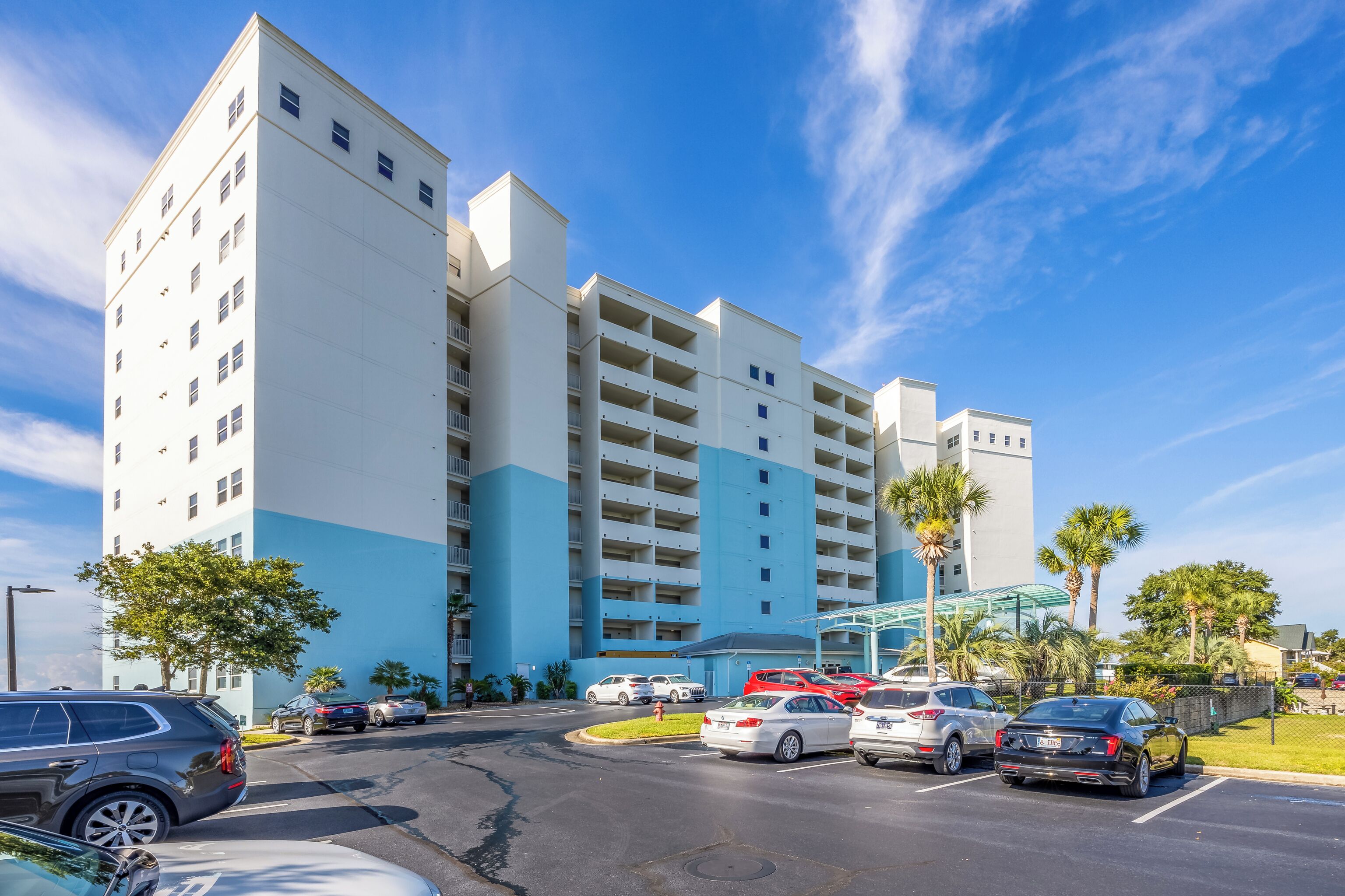 A multi-story hotel with a parking lot in front.