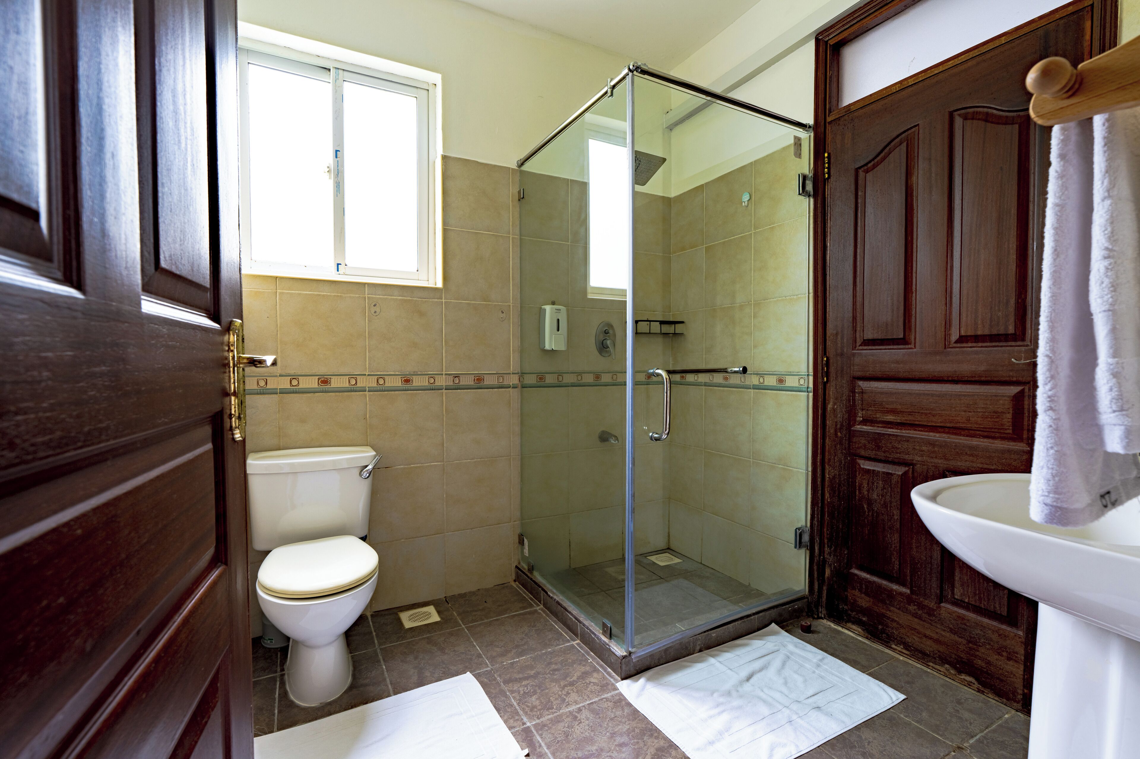 Un baño con cabina de ducha de vidrio, inodoro y lavabo.