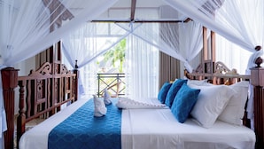 Uma cama com roupa de cama branca e azul, cabeceira de madeira e dossel.