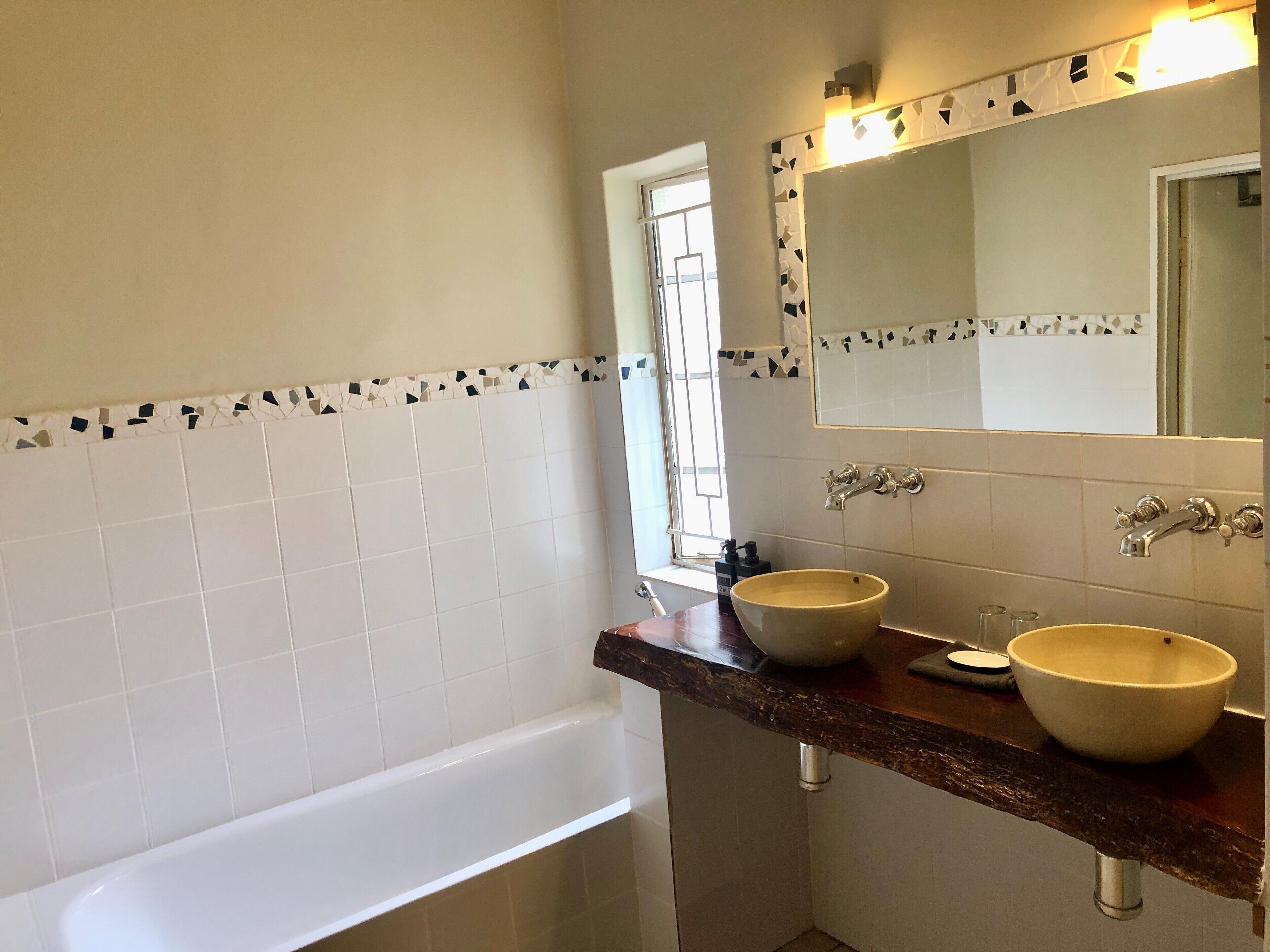 Un baño con dos lavabos, una bañera y una ventana.