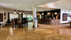 Een ruime lobby met een bar, houten vloeren en geweven tapijten.