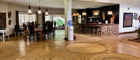 A spacious lobby with a bar area, wooden flooring, and woven rugs.