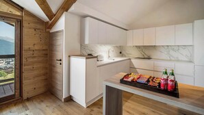 A modern kitchen with white cabinets, a marble backsplash, and a wooden ceiling.