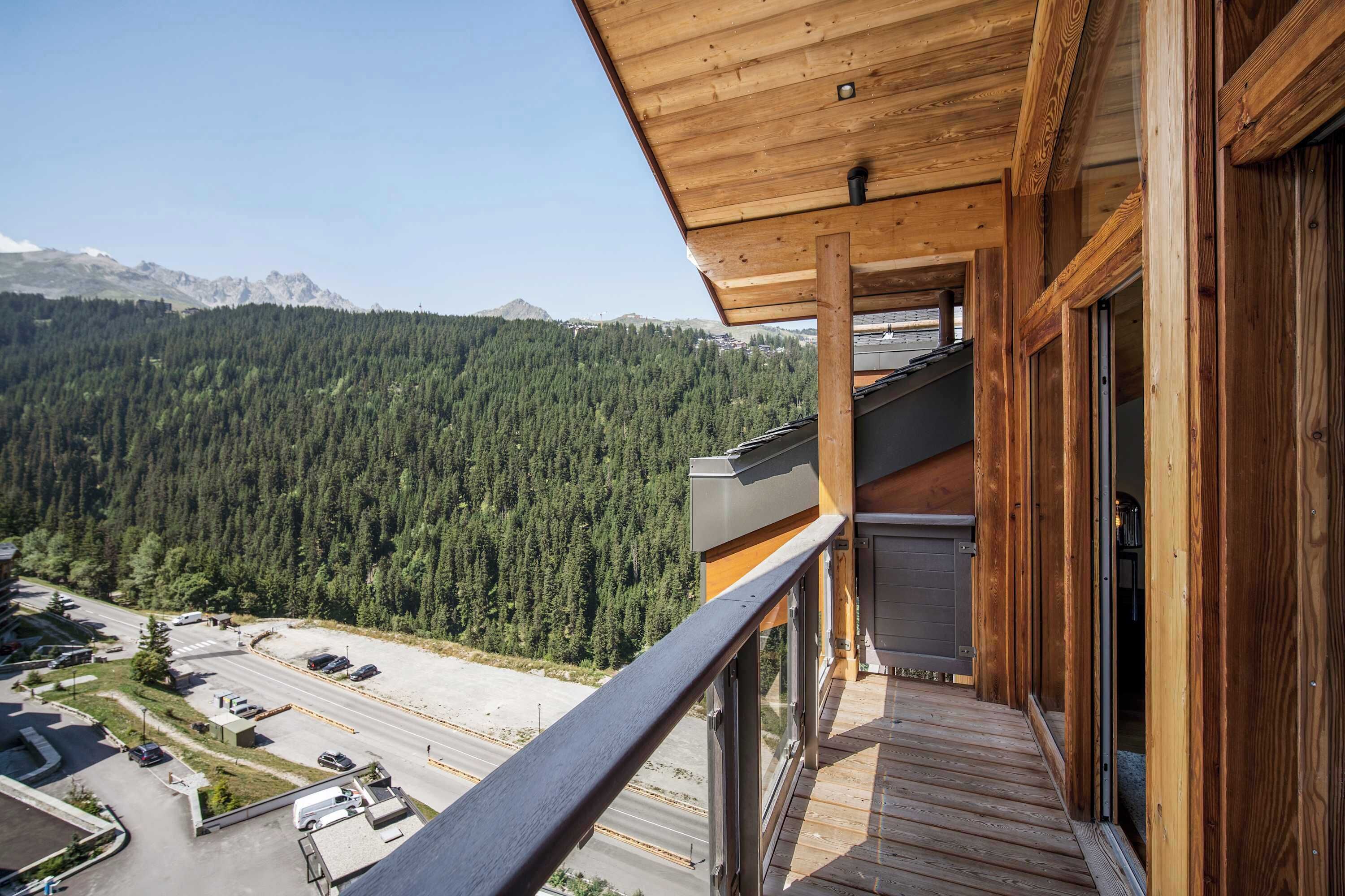 Een houten balkon met uitzicht op een bebost berglandschap.