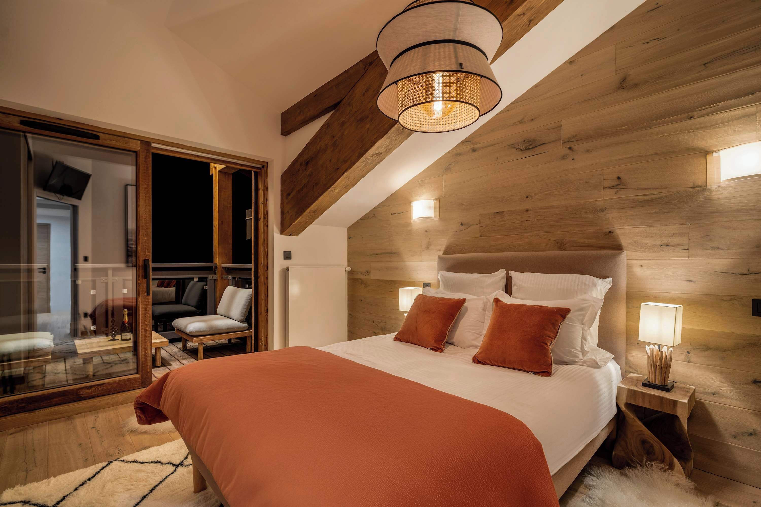 A bedroom with a large bed, wooden headboard, and a glass door leading to a balcony.