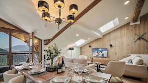 A dining area with a wooden table set for six, surrounded by chairs.