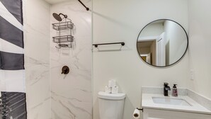 Een badkamer met toilet, wastafel, spiegel en douche.