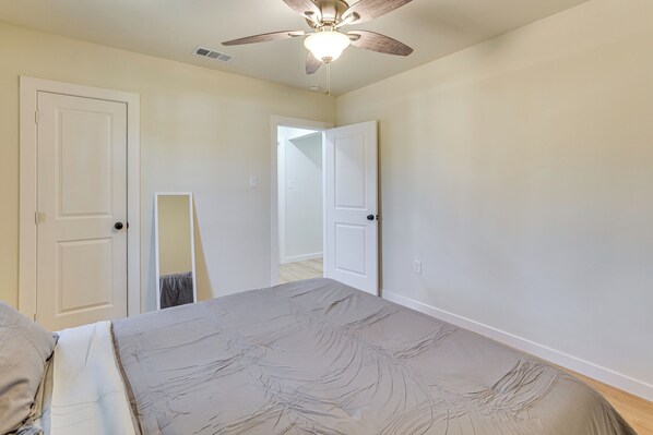 A bedroom with a bed, a ceiling fan, and two doors.