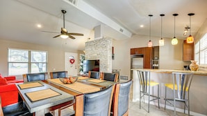 A modern kitchen with a stone accent wall, a dining area with a red couch, and a bar with high stools. - Large Yard: Home 9 Mi to San Antonio River Walk (San Antonio)