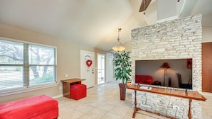 A spacious living room with a stone fireplace, a red sofa, and a wooden coffee table. - Large Yard: Home 9 Mi to San Antonio River Walk (San Antonio)
