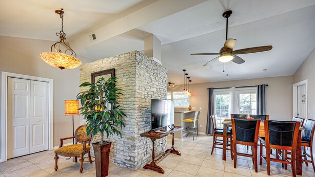 A spacious living room with a stone fireplace, a dining area with wooden chairs, and a ceiling fan. - Large Yard: Home 9 Mi to San Antonio River Walk (San Antonio)