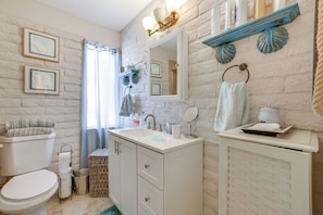 A bathroom with a white sink, a mirror, a toilet, and a shower curtain.