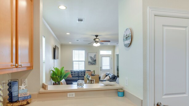 A modern kitchen with a countertop, cabinets, and a ceiling fan.