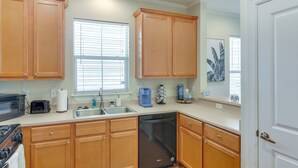 A kitchen with wooden cabinets, a dishwasher, a stove, and a window with blinds.