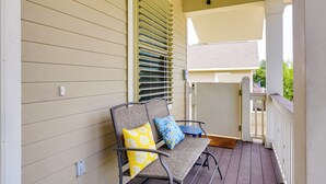 A porch with two chairs, one with a yellow pillow and one with a blue pillow, and a small table.