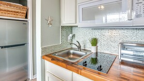 Una cocina con un refrigerador de acero inoxidable, un microondas, un fregadero y una tostadora.