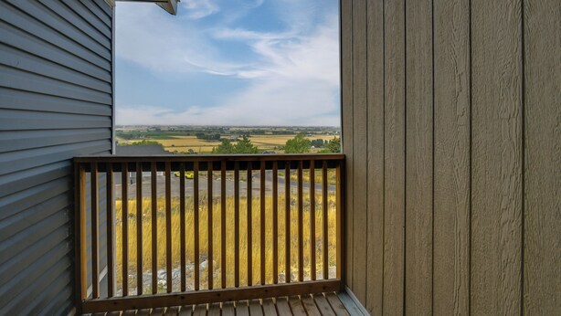 Un balcón de madera con vistas a un paisaje rural.