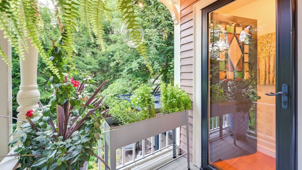 Een balkon met potplanten en uitzicht op een weelderige tuin.
