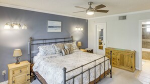 A bedroom with a bed, bedside tables, a ceiling fan, and a wooden cabinet.