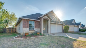A residential house with a brick facade, a garage, and a well-maintained lawn. - Private Yard & Patio: Fort Worth Family Home (Fort Worth)