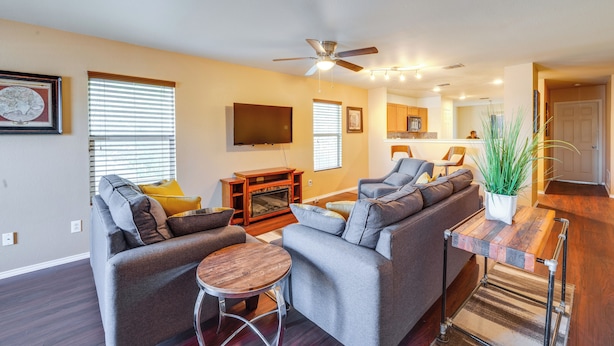 A modern living room with a gray sofa set, a wooden coffee table, and a ceiling fan. - Private Yard & Patio: Fort Worth Family Home (Fort Worth)