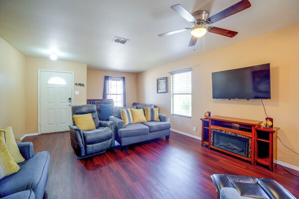 A living room with a fireplace, a ceiling fan, and a flat-screen TV mounted on the wall.