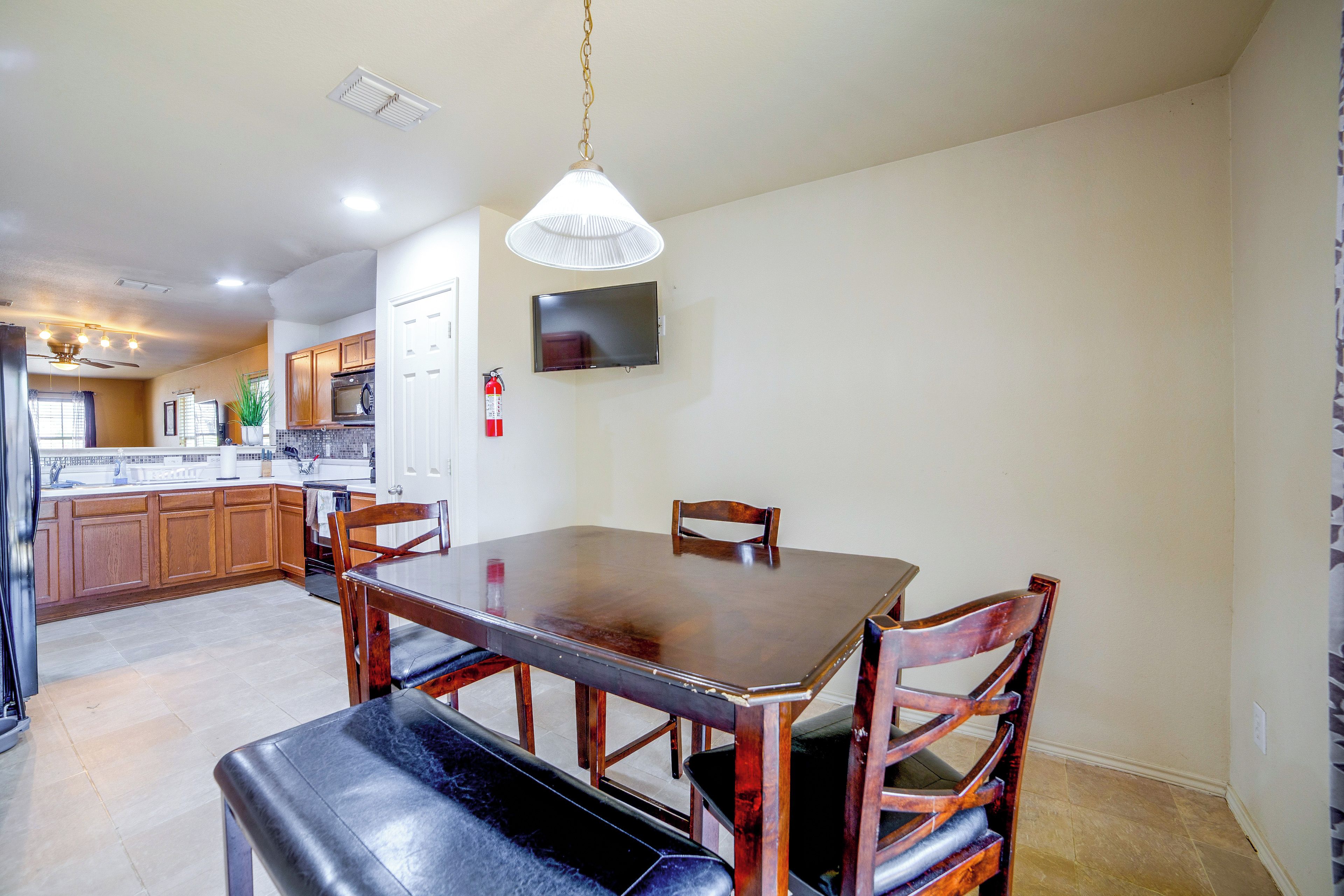 A modern kitchen with wooden cabinets, a dining table, and a built-in oven.