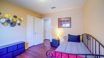 Un dormitorio con cama, cómoda, mesita de noche, lámpara y decoración en la pared.