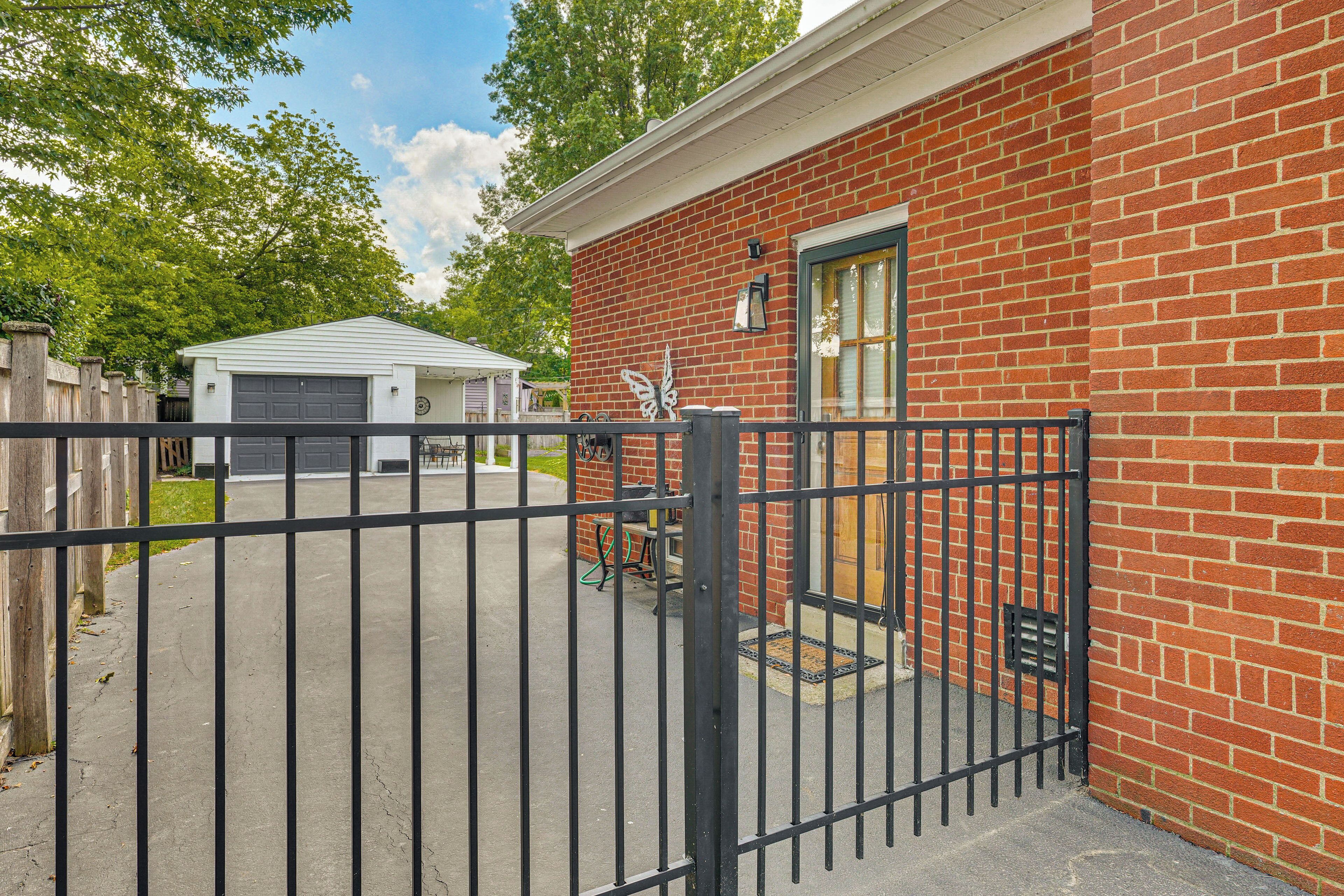 A brick building with a garage, a gated driveway, and a small patio area with outdoor furniture.
