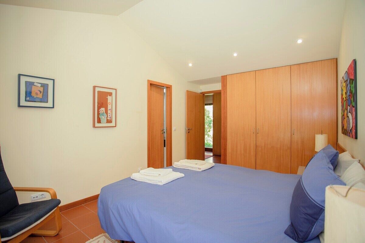 A bedroom with a bed, a chair, and a wardrobe.