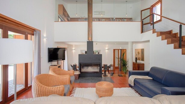 A spacious living area with a fireplace, comfortable seating, and a staircase leading to an upper level. - Liiiving in Caminha Countryside Pool House (Caminha)
