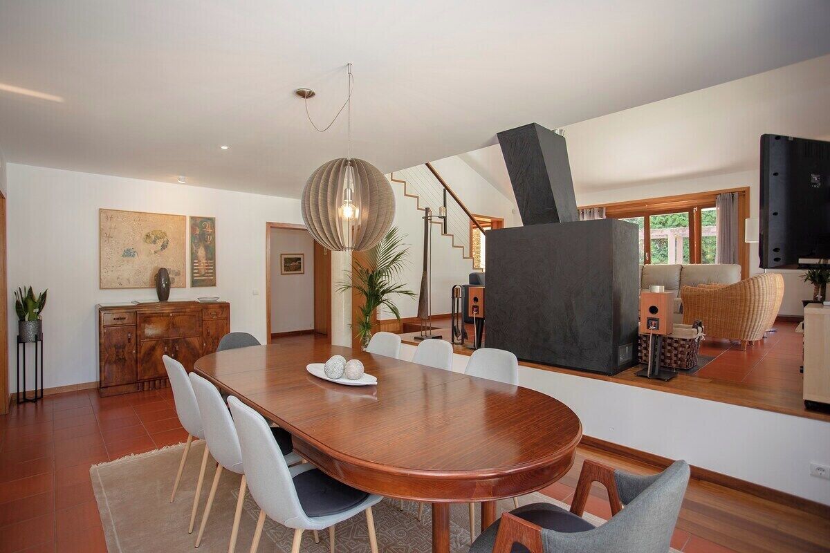 Un espace repas moderne avec une table en bois, des chaises blanches et un luminaire décoratif.