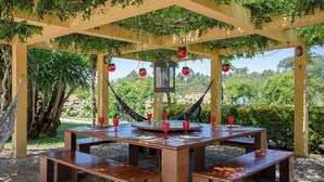 A wooden pergola with a table and benches, surrounded by greenery and a clear view of the landscape. - Liiiving in Caminha Countryside Pool House (Caminha)