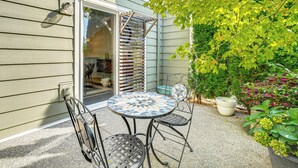A patio with a round table and chairs, a covered entryway, and potted plants.