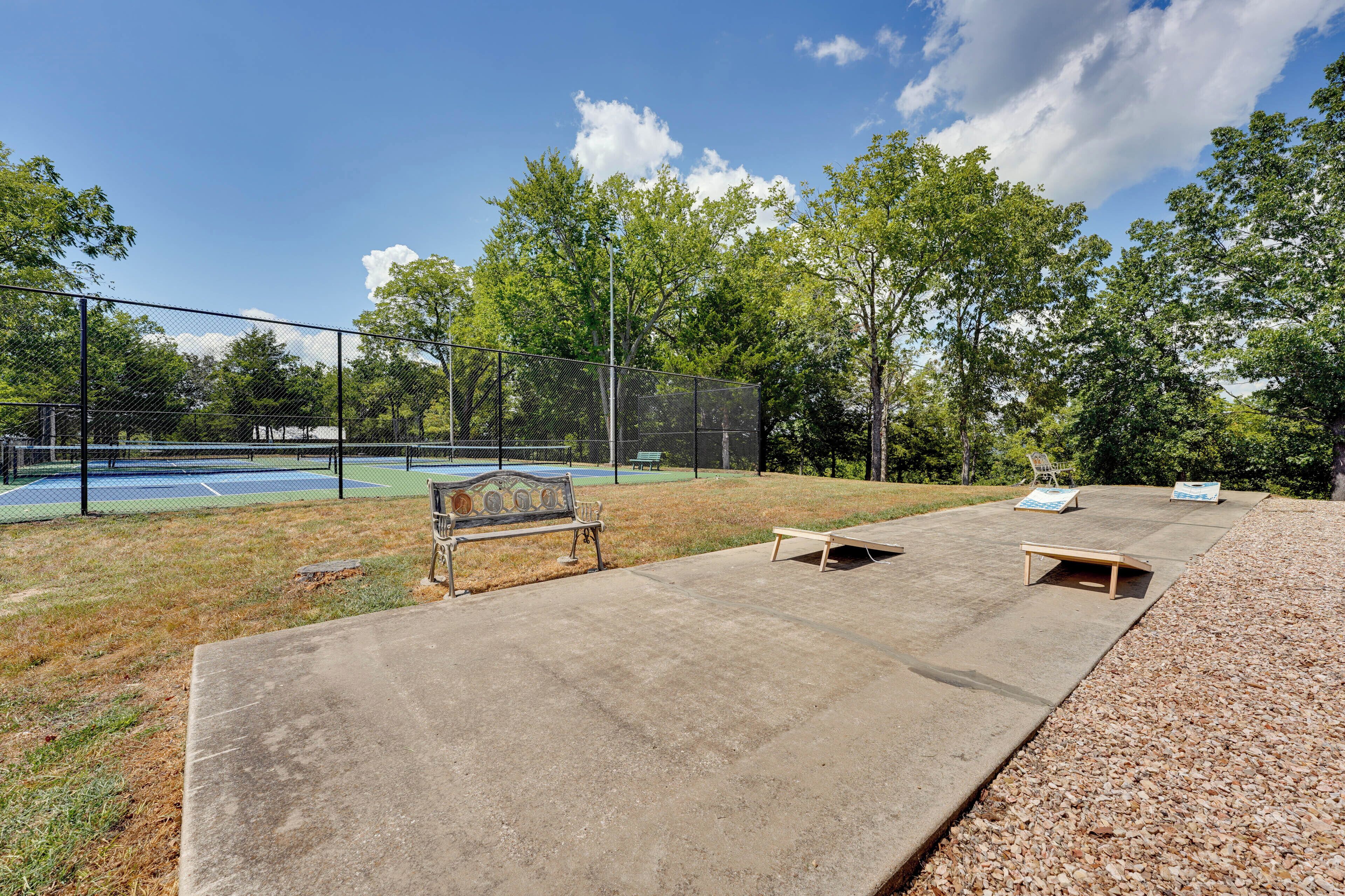 Un court de tennis avec des bancs et une table de pique-nique, situé dans un parc.