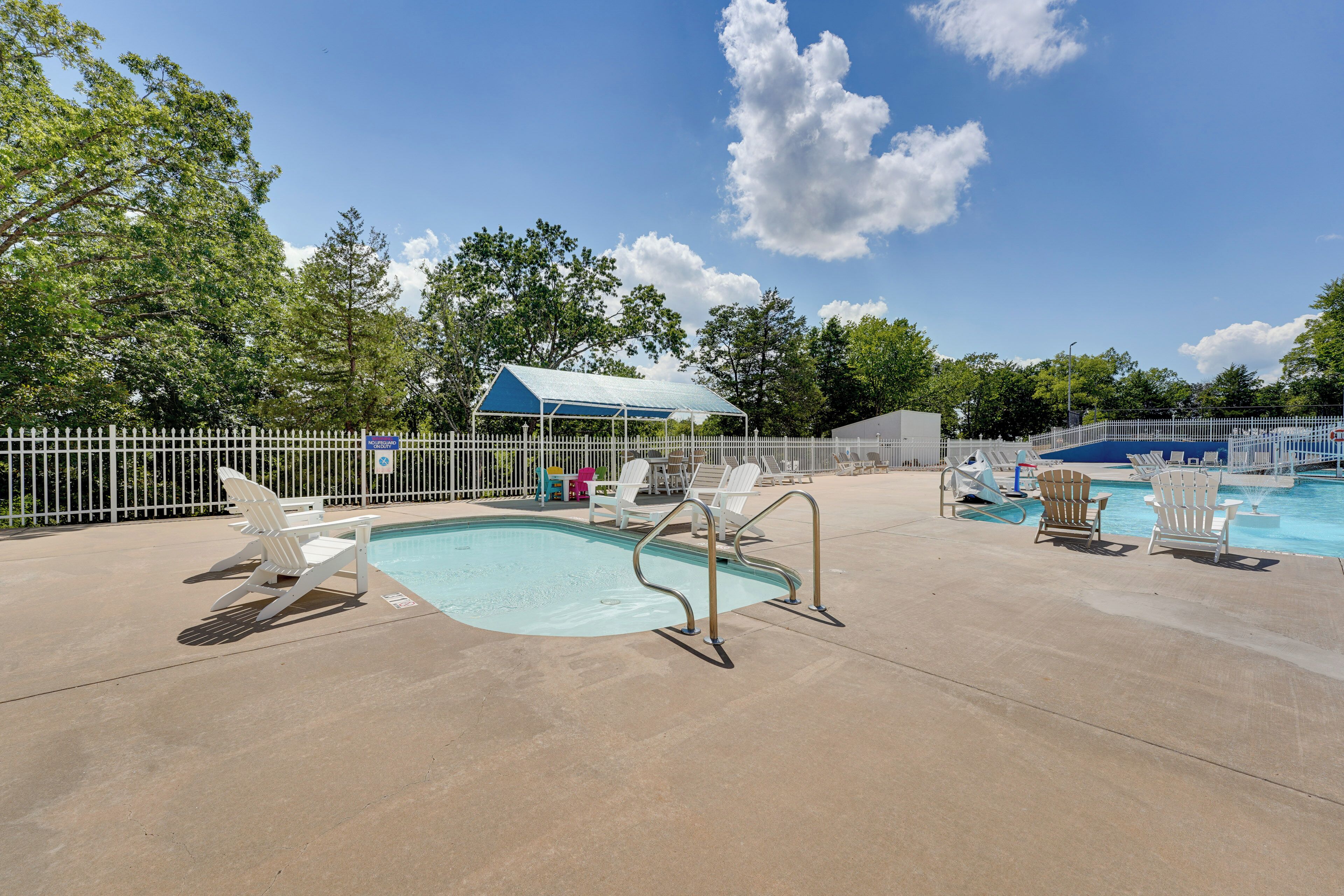 A pool area with lounge chairs and a covered seating area.