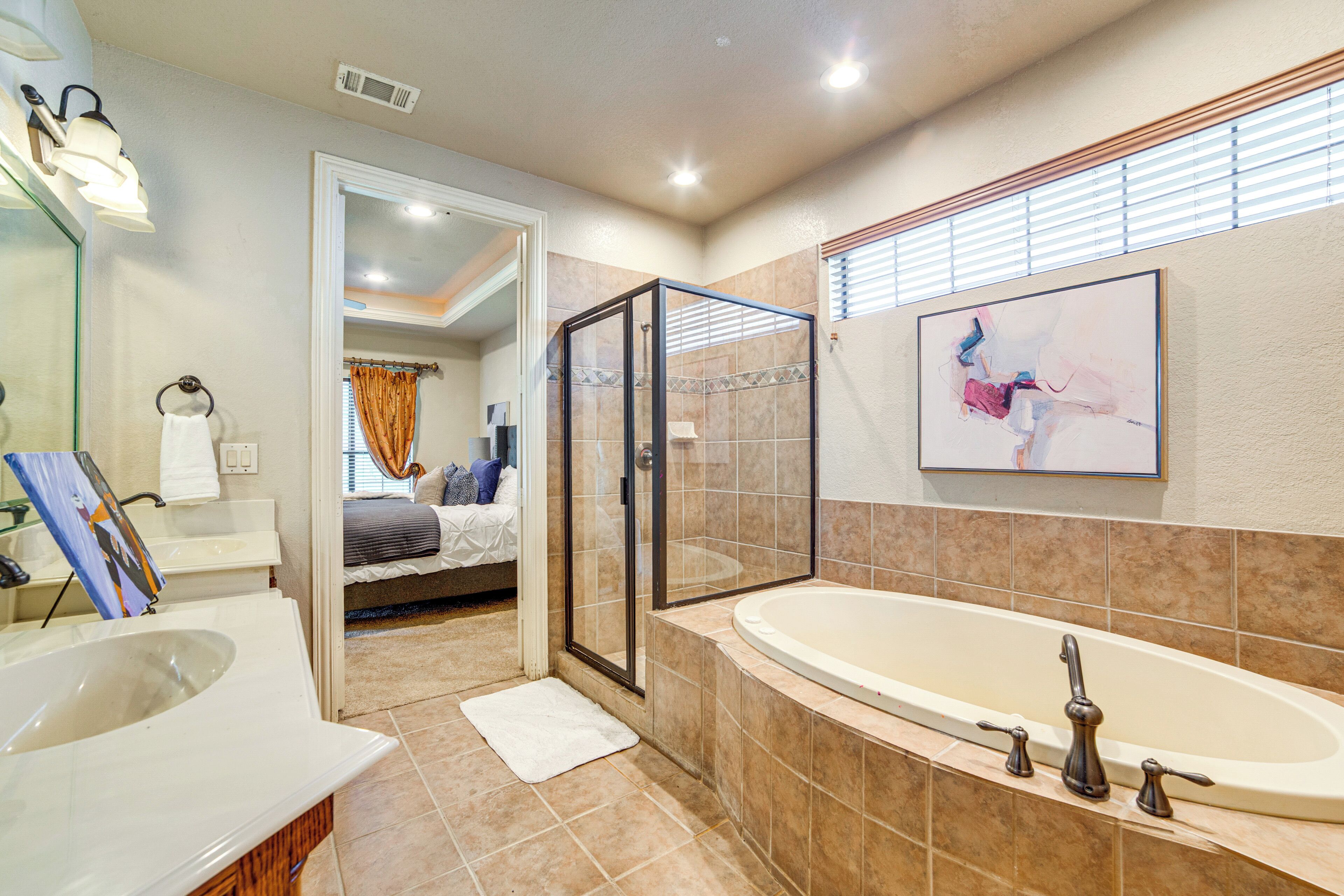 A modern bathroom with a large bathtub, a glass-enclosed shower, and a walk-in closet.