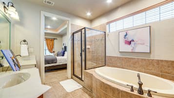 A modern bathroom with a large bathtub, a glass-enclosed shower, and a walk-in closet.