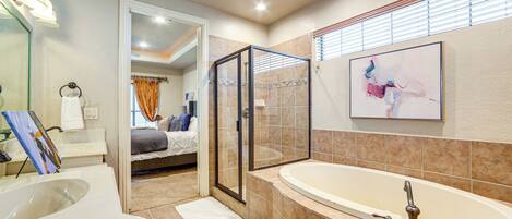 A modern bathroom with a large bathtub, a glass-enclosed shower, and a walk-in closet.