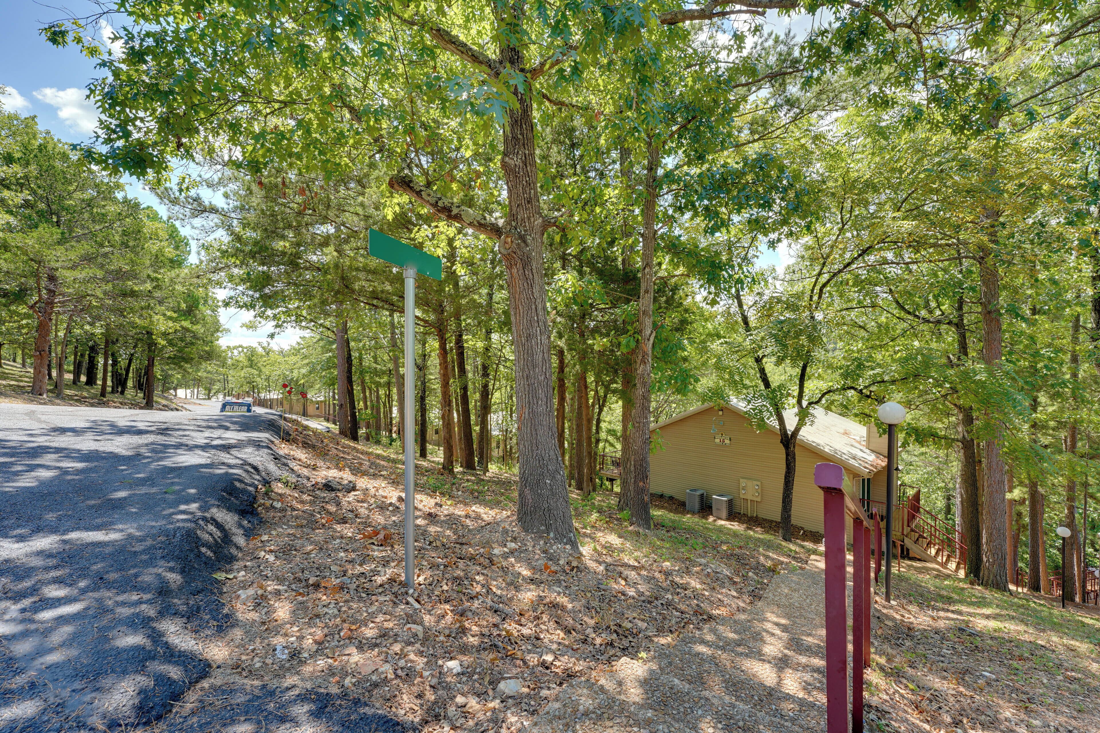 A road with a signpost and a building in a wooded area.