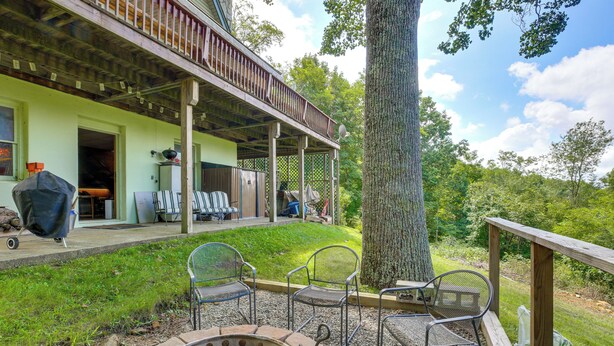 A covered outdoor area with a barbecue grill, chairs, and a wooden deck. - Deck, Fire Pit, Games: Family Escape Near Boone (Zionville)