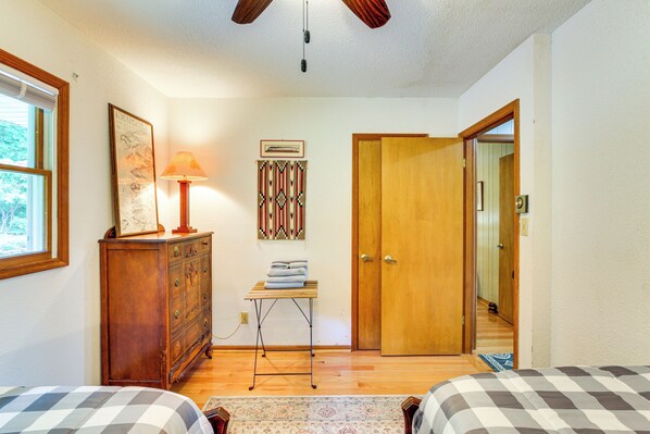 A bedroom with two beds, a wooden dresser, a lamp, and a door leading to another room. - Deck, Fire Pit, Games: Family Escape Near Boone (Zionville)