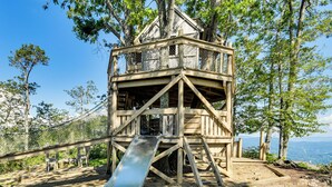 A wooden treehouse with a slide, surrounded by trees and a clear view of the landscape. - 6 Mi to Pisgah Nat'l Forest! Condo w/ Serene Views (Burnsville)
