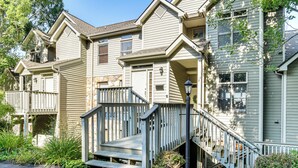 A multi-story residential building with a front porch, a staircase, and a small garden area. - 6 Mi to Pisgah Nat'l Forest! Condo w/ Serene Views (Burnsville)