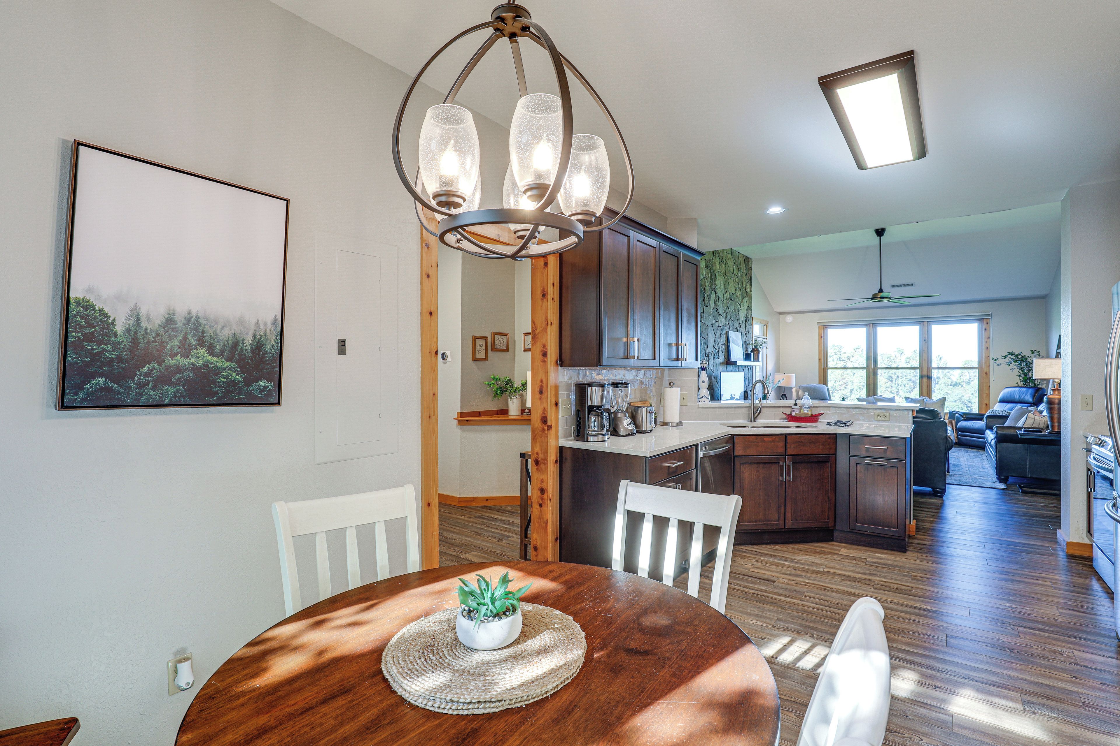 A modern kitchen with wooden cabinets, a dining table with chairs, and a large window.