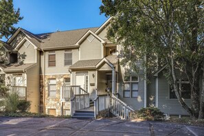 A two-story house with a stone facade, a front porch, and a staircase leading to the entrance. - Stunning Blue Ridge Views & Modern Mountain Ease (Burnsville)